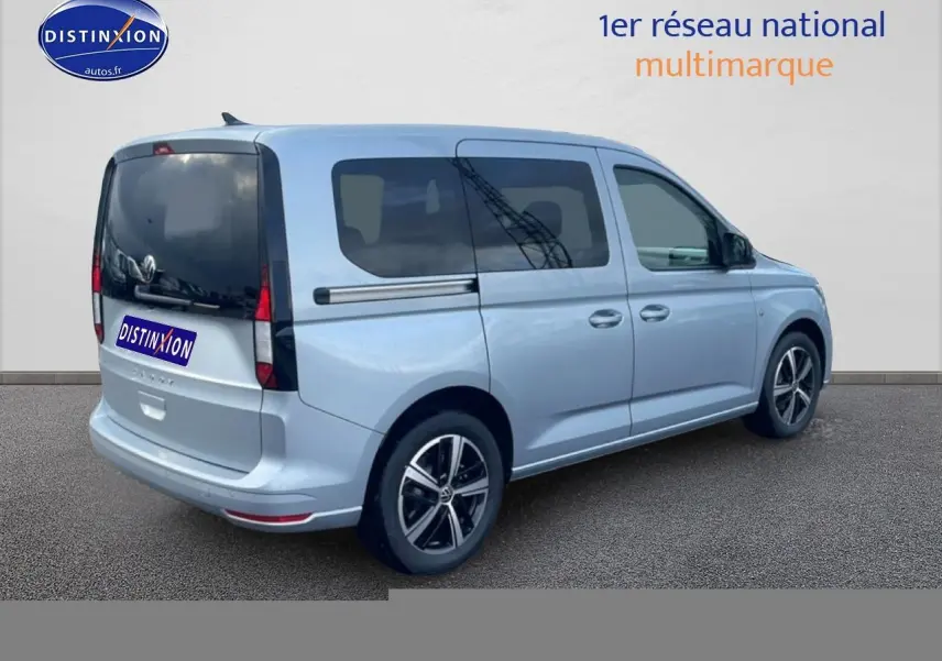 Vue 3/4 arrière droite d'un Volkswagen Caddy gris argent 2025 avec vitres arrière teintées et jantes alliage.