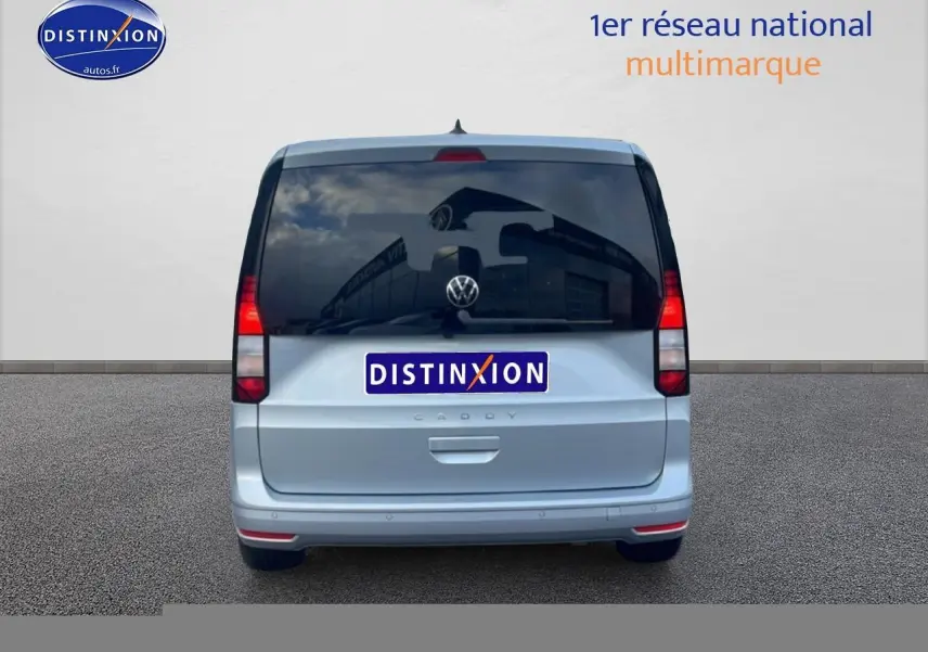 Vue arrière d'un Volkswagen Caddy gris argent 2025 avec vitres arrière teintées et feux rouges verticaux.