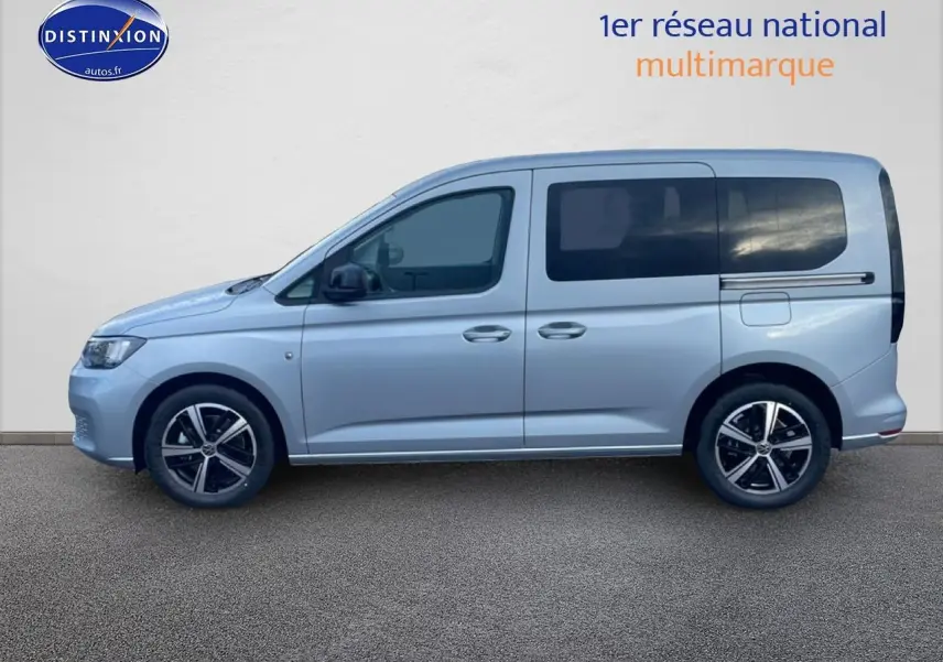 Vue de profil côté gauche d'un Volkswagen Caddy gris argent 2025 avec vitres arrière teintées et jantes alliage.