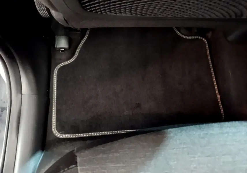 Vue intérieure du plancher arrière côté droit d'un Hyundai Kona électrique avec tapis de sol noir à surpiqûres claires.