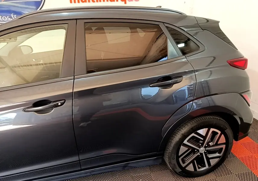 Vue latérale droite d'une Hyundai Kona électrique 2021 gris foncé avec jantes spécifiques et vitres teintées.