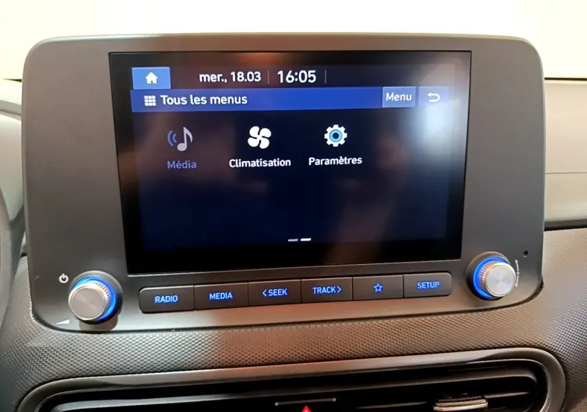 Écran tactile central affichant les menus média, climatisation et paramètres dans l’habitacle d’une Hyundai Kona électrique.
