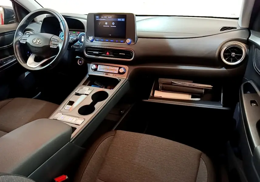 Intérieur noir et gris de la Hyundai KONA électrique 2021, vue de face côté conducteur avec tableau de bord et écran tactile.