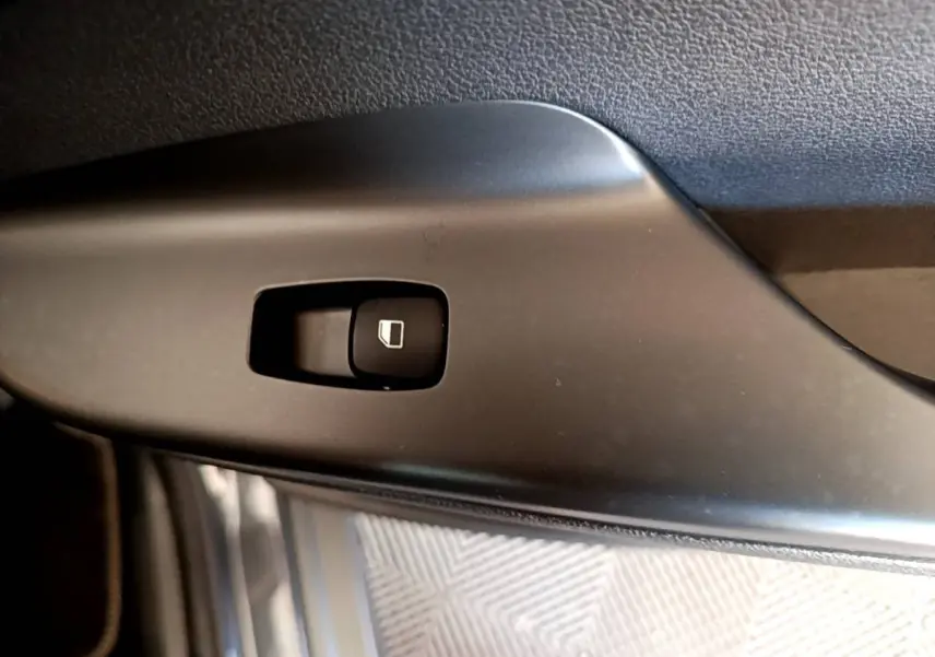Gros plan sur le bouton de commande de lève-vitre côté conducteur d’un Hyundai Kona électrique 2021, intérieur noir.