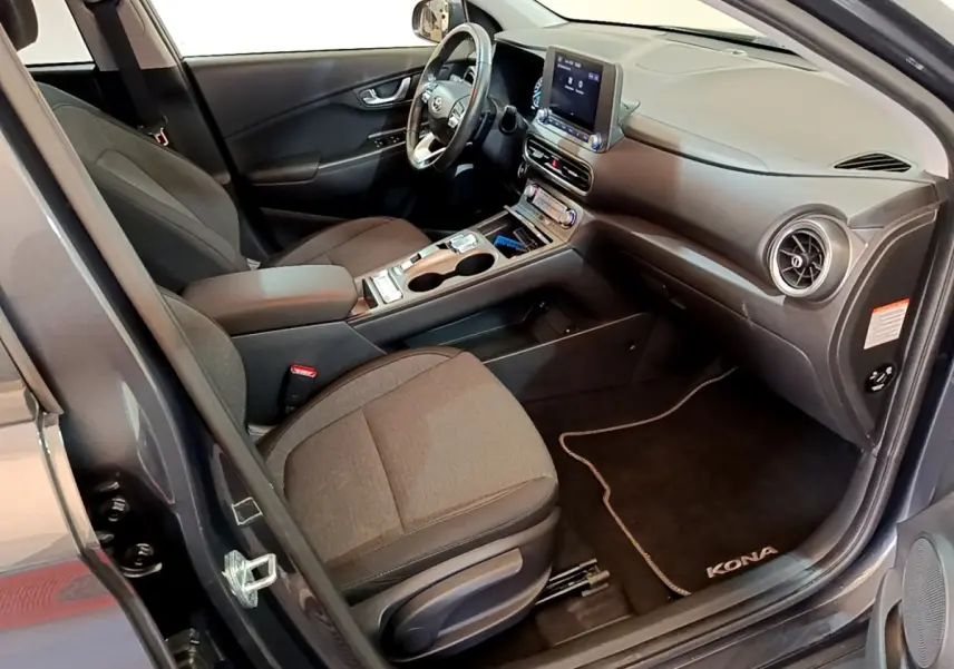 Vue intérieure côté conducteur du Hyundai Kona électrique 2021, sièges gris et tableau de bord avec écran tactile.