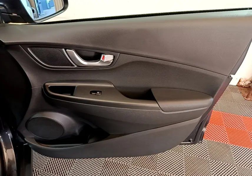 Vue intérieure côté gauche de la porte avant d'une Hyundai Kona électrique 2021, avec garniture noire et poignée argentée.