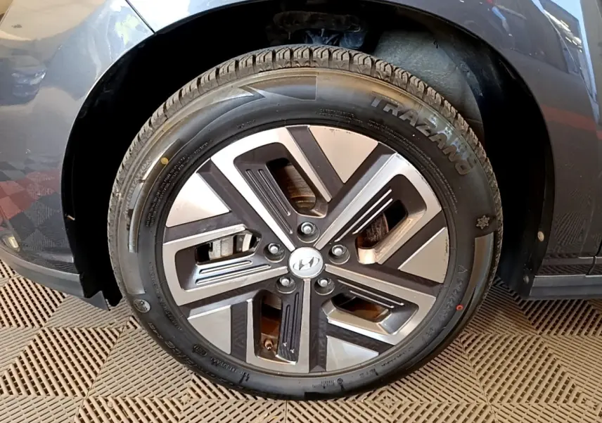 Gros plan sur la roue avant droite d'une Hyundai Kona électrique gris foncé avec jante alliage bicolore.