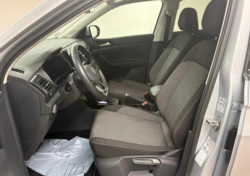 Vue intérieure côté conducteur du Volkswagen T-Cross 2024 argent avec sièges tissu gris et volant multifonction.