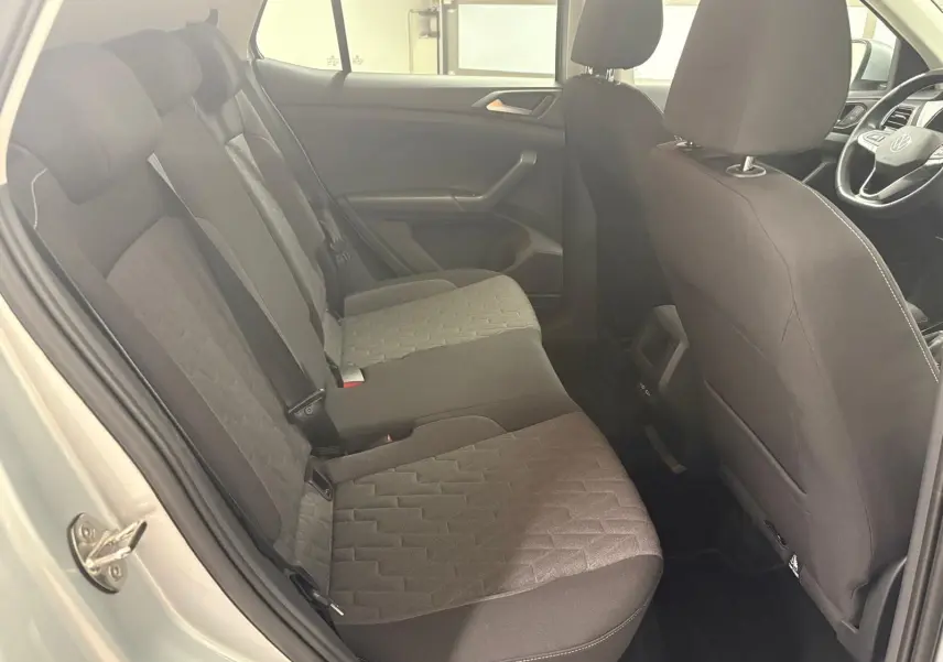 Vue intérieure côté gauche sur la banquette arrière et sièges avant noirs du Volkswagen T-Cross reflet d'argent 2024.