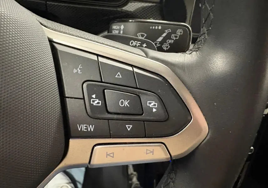 Gros plan sur les commandes multifonctions noires et argent du volant cuir du Volkswagen T-Cross 2024.