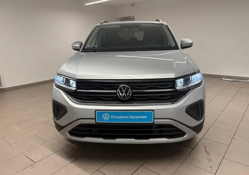 Vue frontale d'un Volkswagen T-Cross 2024 en reflet d'argent, avec phares LED allumés et plaque "Occasions Garantis".