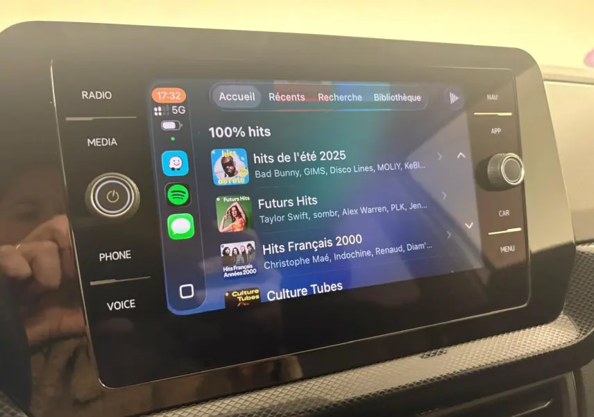 Écran tactile central du Volkswagen T-Cross 2024 en reflet d'argent, affichant l'interface multimédia avec playlists musicales.