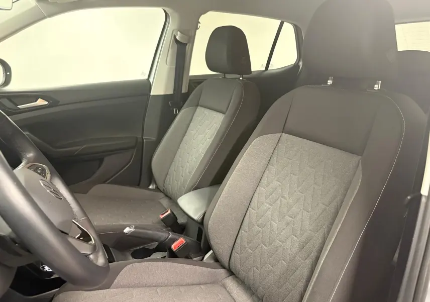 Vue intérieure côté avant droit du Volkswagen T-Cross 2024, sièges tissu gris avec motifs géométriques et accoudoir central.