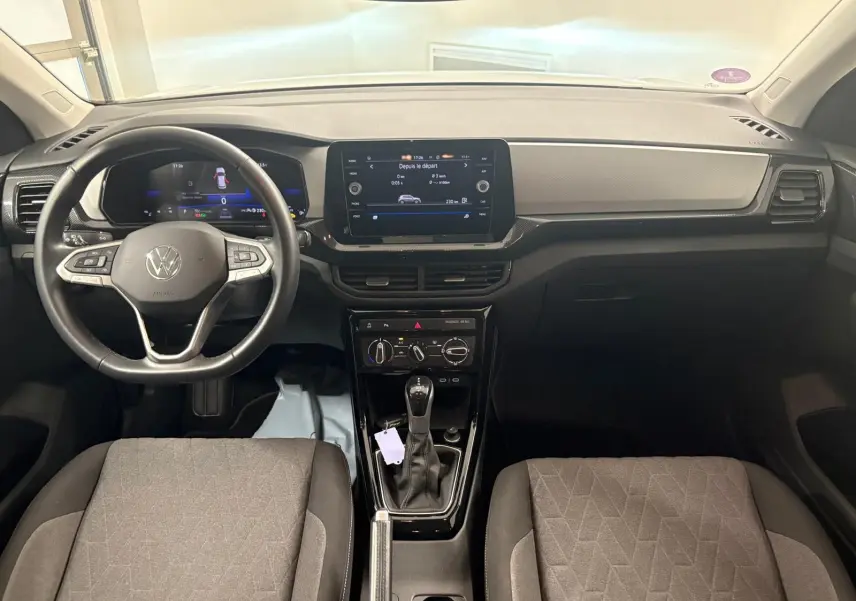 Vue intérieure avant du Volkswagen T-Cross 2024, tableau de bord noir avec écran tactile central et volant multifonction cuir.