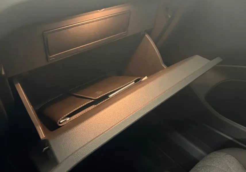 Gant de boîte à gants ouvert côté passager avec un étui noir à l'intérieur, intérieur sombre du Volkswagen T-Cross.