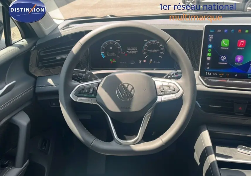 Vue intérieure centrée sur le volant noir du Volkswagen Tiguan 1.5 TSI 130ch avec tableau de bord numérique et écran tactile.