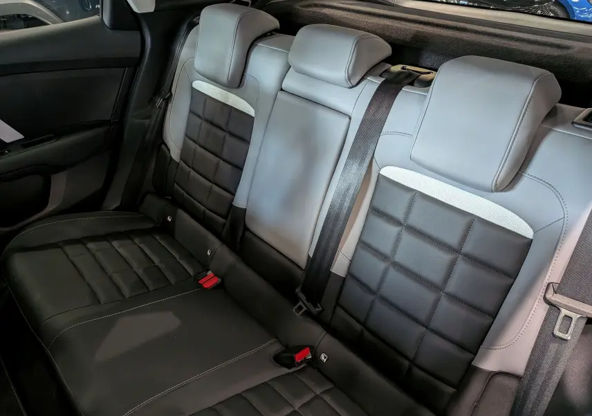 Vue intérieure de la banquette arrière en cuir noir et gris clair du Citroën C4 Hybride 2025, avec ceintures de sécurité visibles.