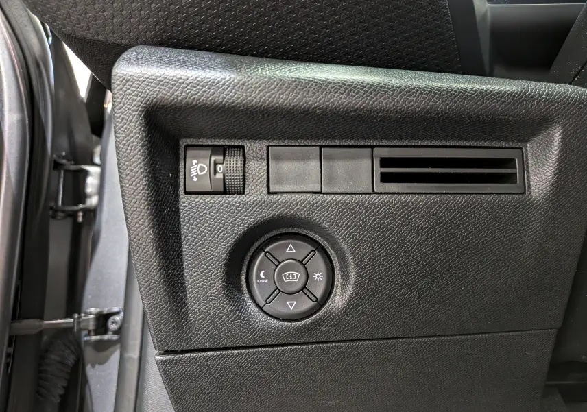 Vue rapprochée du panneau de commandes côté gauche intérieur d'une Citroën C4 gris Mercury, avec réglage des phares et ventilation.