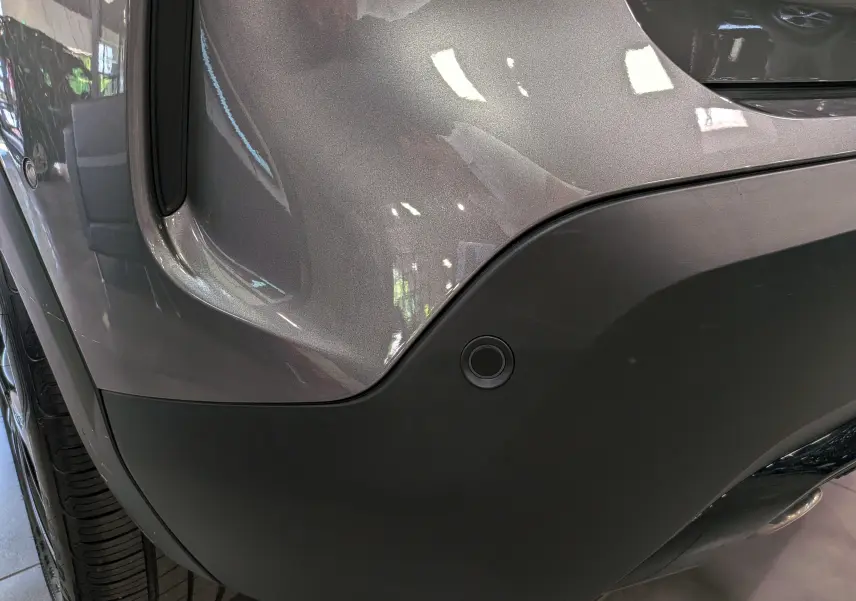 Gros plan sur l'angle arrière droit gris Mercury du Citroën C4 hybride, mettant en valeur le capteur de stationnement intégré.