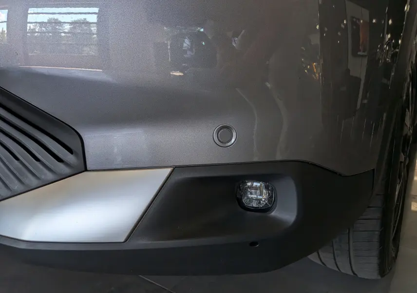 Gros plan sur le pare-chocs avant gris Mercury du Citroën C4 hybride 2025 avec feu antibrouillard et capteur de stationnement.