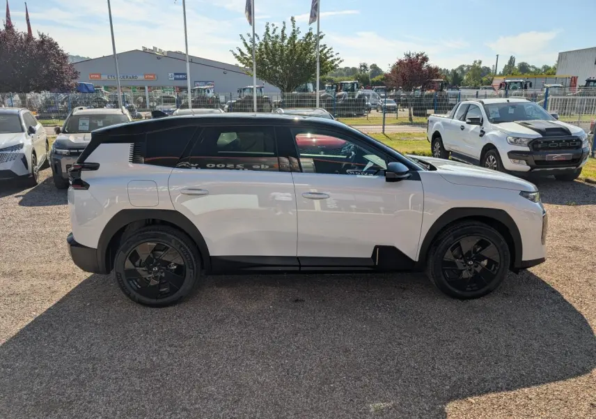 Vue de profil côté gauche d'un Citroën C5 Aircross blanc avec toit noir et jantes noires sur parking extérieur.
