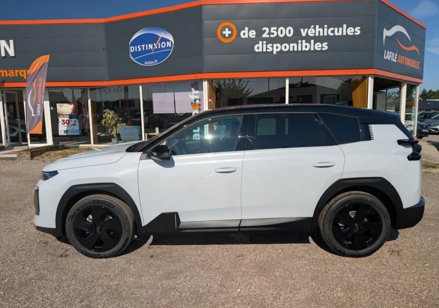 Vue latérale gauche du Citroën C5 Aircross blanc avec toit noir et jantes alliage noires, devant un concessionnaire.