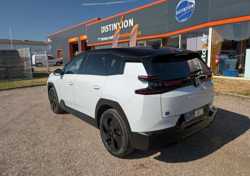 Vue 3/4 arrière droite du Citroën C5 Aircross blanc avec toit noir et jantes alliage noires sur parking.