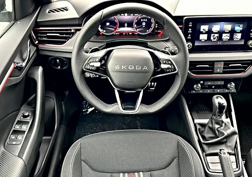 Vue intérieure centrée sur le volant sport et tableau de bord numérique du Skoda Kamiq Monte Carlo, finition noire avec inserts rouges.
