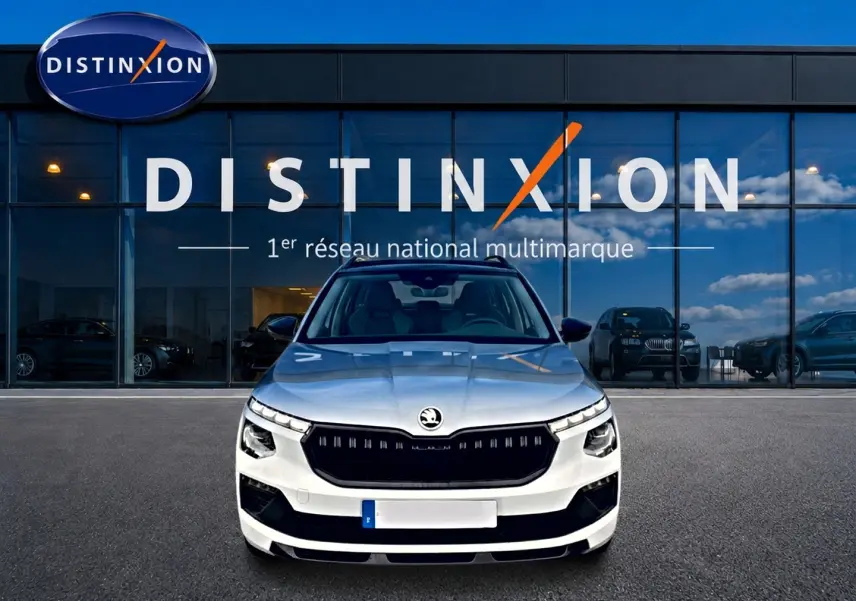 Vue frontale d'un Skoda Kamiq blanc nacré avec calandre noire, garé devant une vitrine Distinxion.