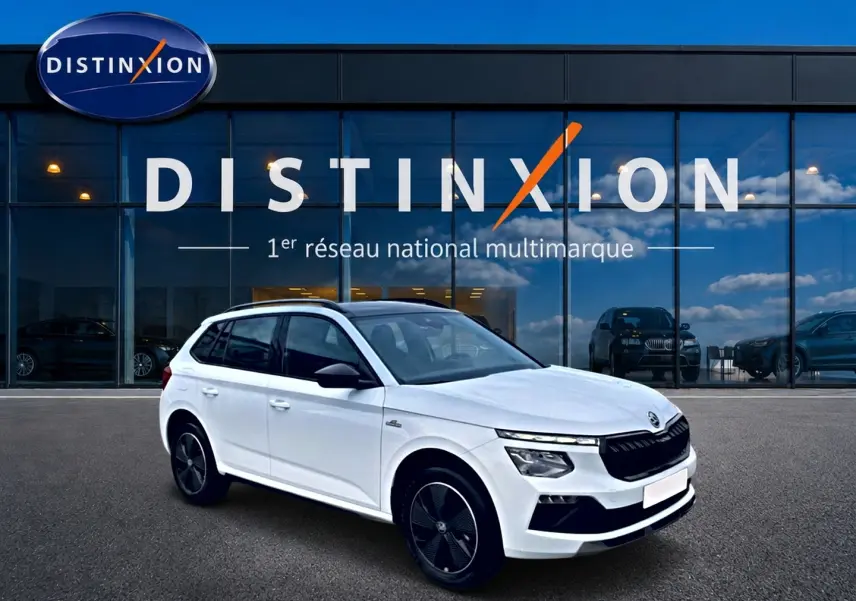Skoda Kamiq blanc nacré en 3/4 avant droit, avec toit panoramique et jantes alu noires distinctives.