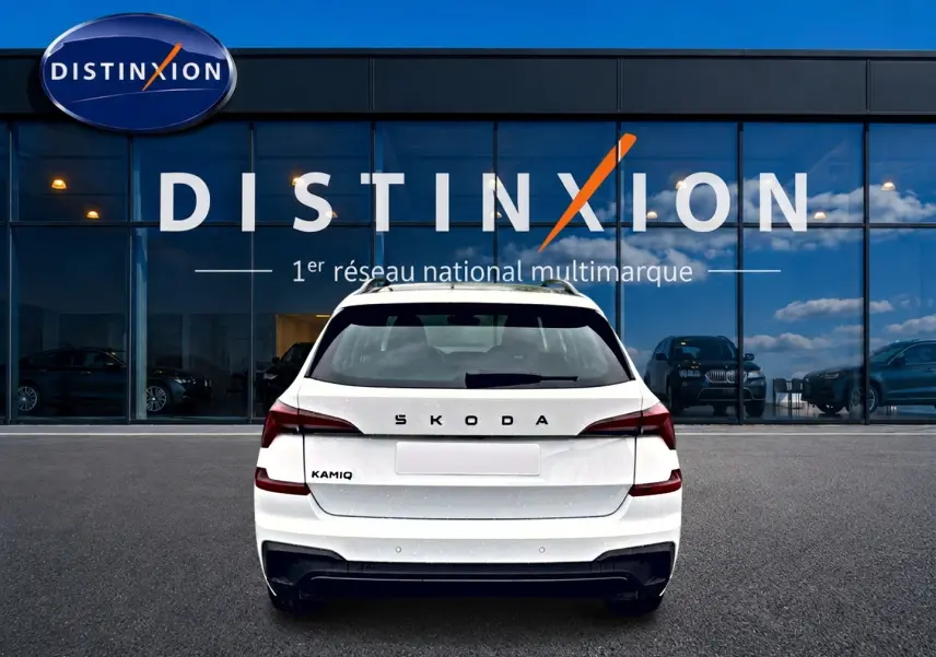 Vue arrière d'un Skoda Kamiq blanc nacré garé devant une vitrine avec logo Distinxion.