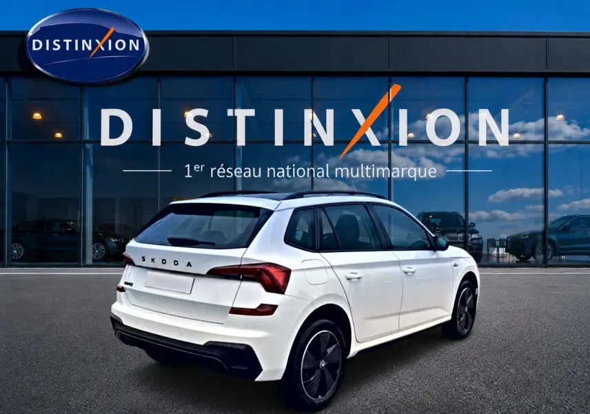 Vue 3/4 arrière droite d'un Skoda Kamiq blanc nacré avec jantes noires et toit panoramique en verre.