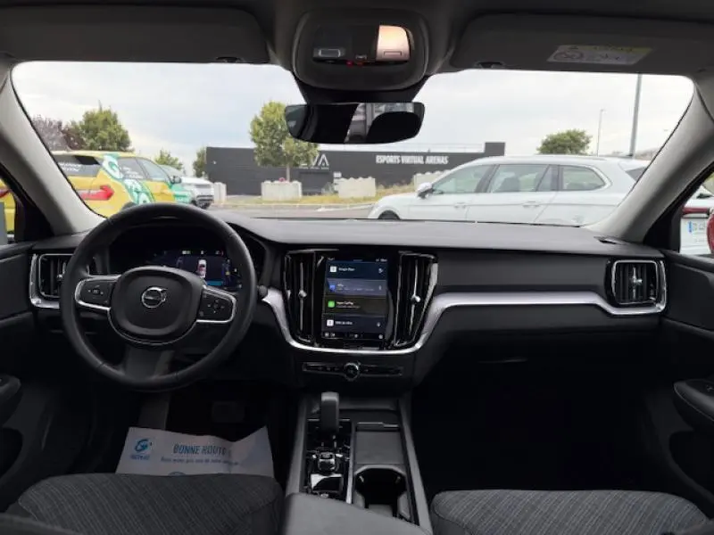Vue intérieure avant de la Volvo S60 2024, tableau de bord noir avec écran tactile central et volant multifonction.