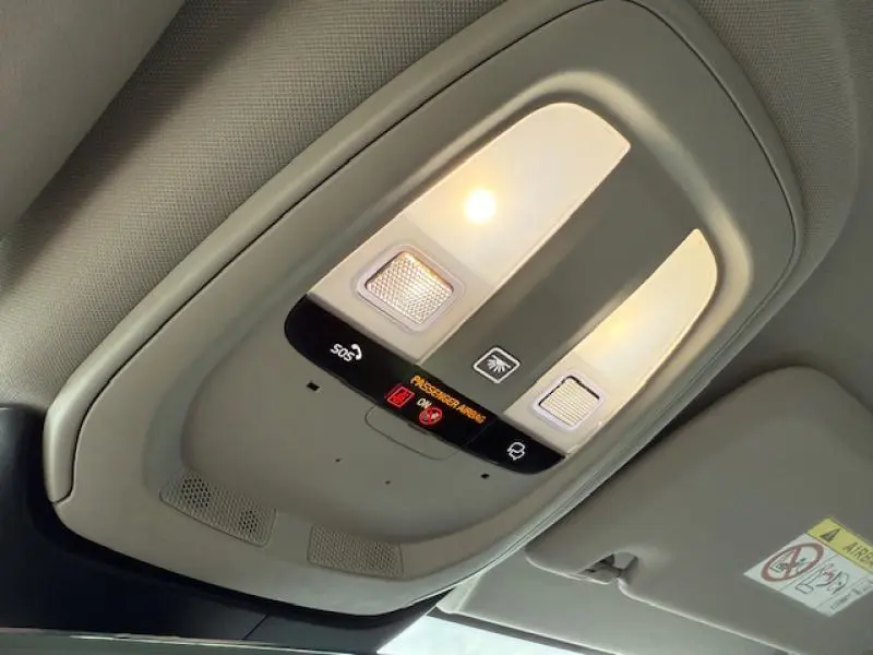 Plafonnier intérieur avec éclairage et commandes, montrant le système SOS et l'indicateur airbag du Volvo S60 2024 rouge fusion métallisé.