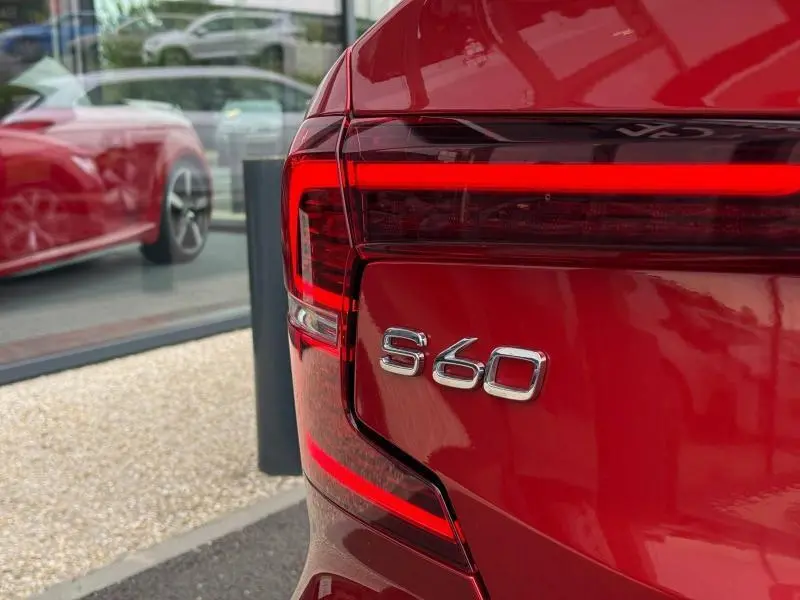Gros plan sur l'arrière droit rouge métallisé du Volvo S60 2024 avec feux LED et logo S60 bien visibles.