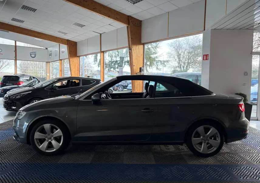 Vue arrière d'une Audi A3 Cabriolet gris métallisé de 2014 avec double sortie d'échappement et capote noire fermée.