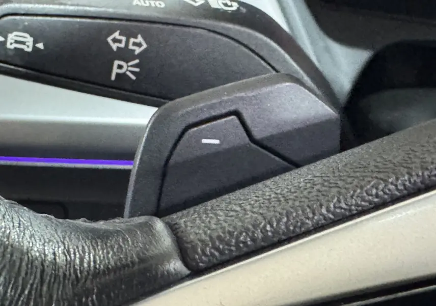 Gros plan sur la palette de commande au volant en cuir noir de l'Audi Q4 E-TRON gris foncé, avec commandes lumineuses.