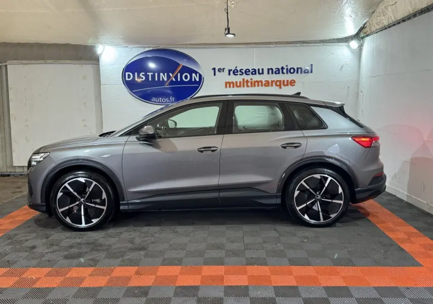Audi Q4 E-TRON gris foncé vue de profil côté gauche, avec jantes noires et détails noirs sur bas de caisse.