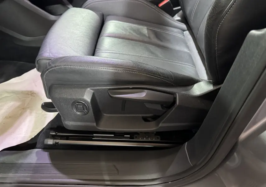 Gros plan sur le siège avant gauche en cuir noir de l'Audi Q4 E-TRON gris foncé, montrant les commandes manuelles.