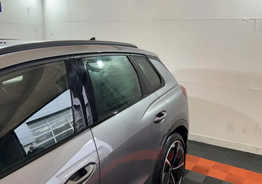 Vue côté gauche arrière d'un Audi Q4 E-TRON gris foncé avec jante noire et toit ouvrant visible