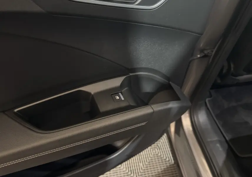 Gros plan sur la poignée intérieure et le bouton de verrouillage de la porte côté conducteur d'un Audi Q4 E-TRON gris foncé.