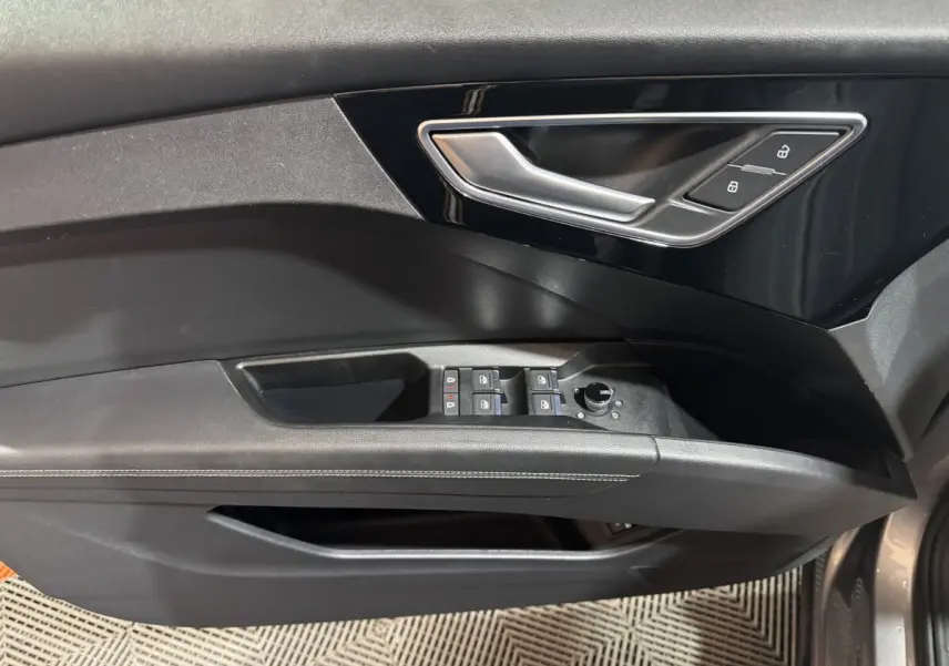 Poignée de porte intérieure côté gauche noire avec commandes de vitres et verrouillage sur Audi Q4 E-TRON gris foncé.