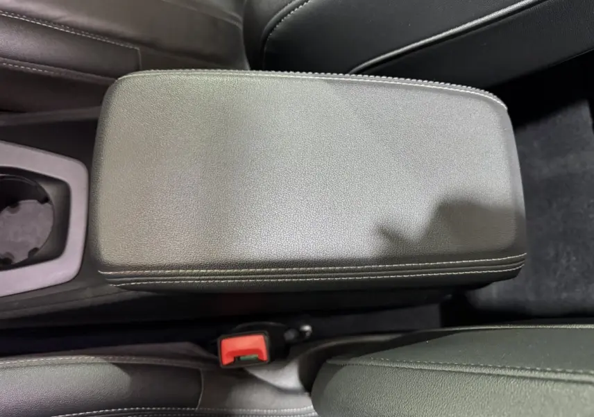 Gros plan sur l'accoudoir central en cuir noir avec surpiqûres blanches de l'Audi Q4 E-TRON gris foncé.