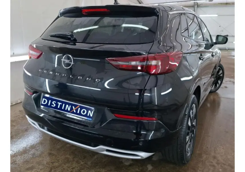 Opel Grandland noir vue de profil côté gauche, jantes alliage bicolores, intérieur showroom avec mur orange.