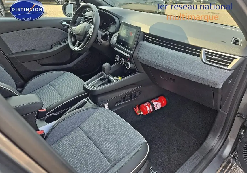 Vue intérieure avant droite de la Renault Clio V gris schiste, montrant sièges sport, console centrale et écran tactile.