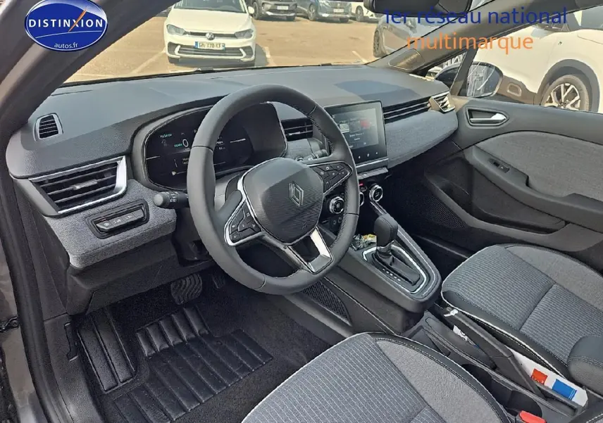 Vue intérieure avant droite de la Renault Clio V 1.6 e-tech 145 techno avec sellerie grise et tableau de bord moderne.