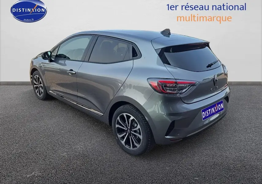 Renault Clio V gris schiste vue 3/4 arrière droit, jantes alu et vitres arrière surteintées visibles.