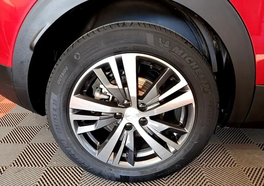 Gros plan sur la roue avant droite du Peugeot 3008 hybride rechargeable rouge avec jante alliage à design moderne.