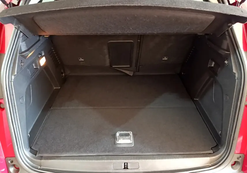 Coffre ouvert rouge du Peugeot 3008 1.6 Hybrid 225, vue arrière montrant l’espace de chargement vide et tapis noir.