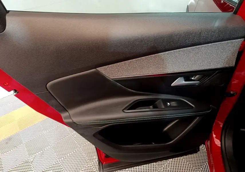 Vue intérieure de la porte arrière gauche rouge du Peugeot 3008 1.6 Hybrid 225 Allure Pack avec garniture noire et grise.